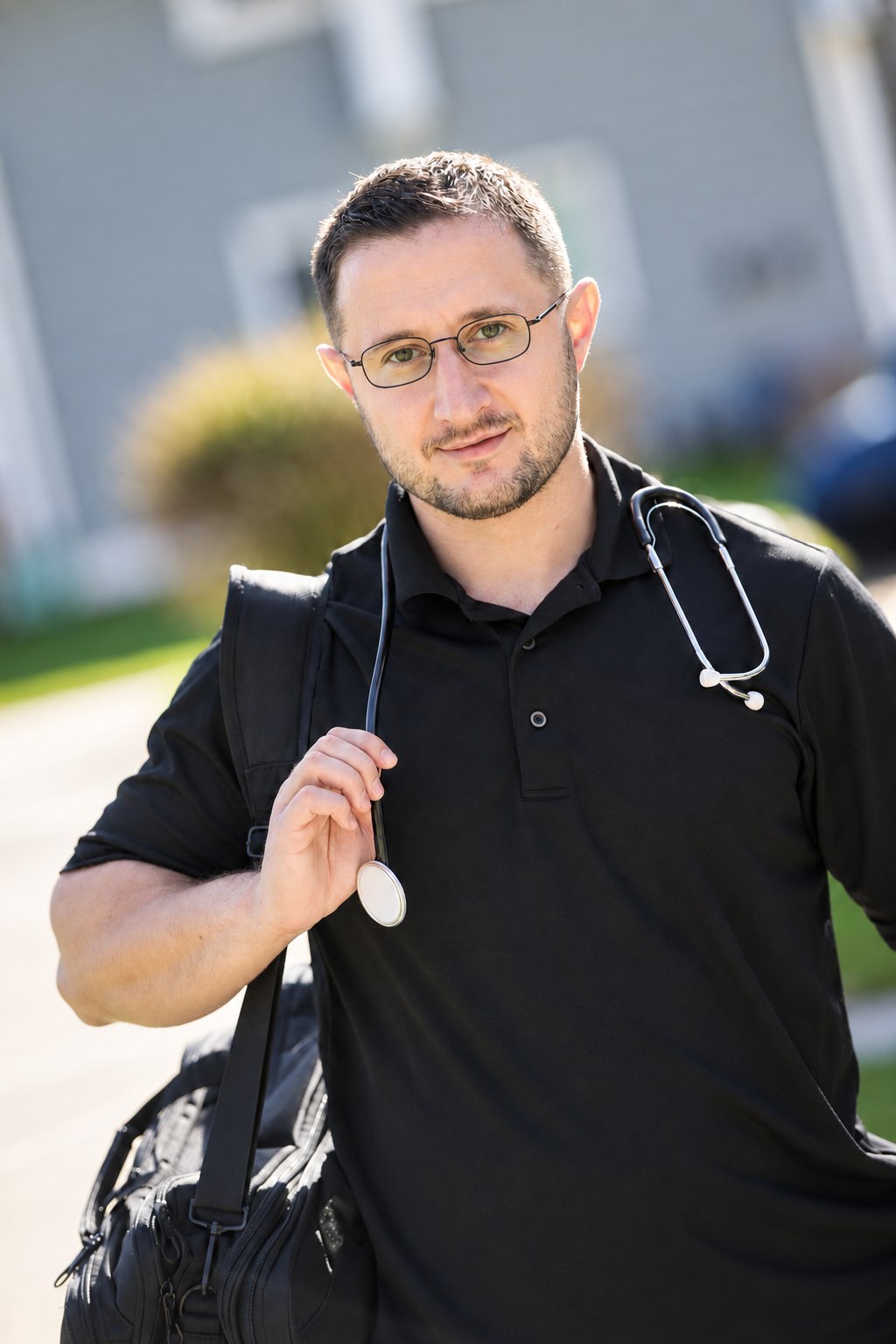 Dr. Lenny Klichinsky in a plain black polo, carrying his equipment bag